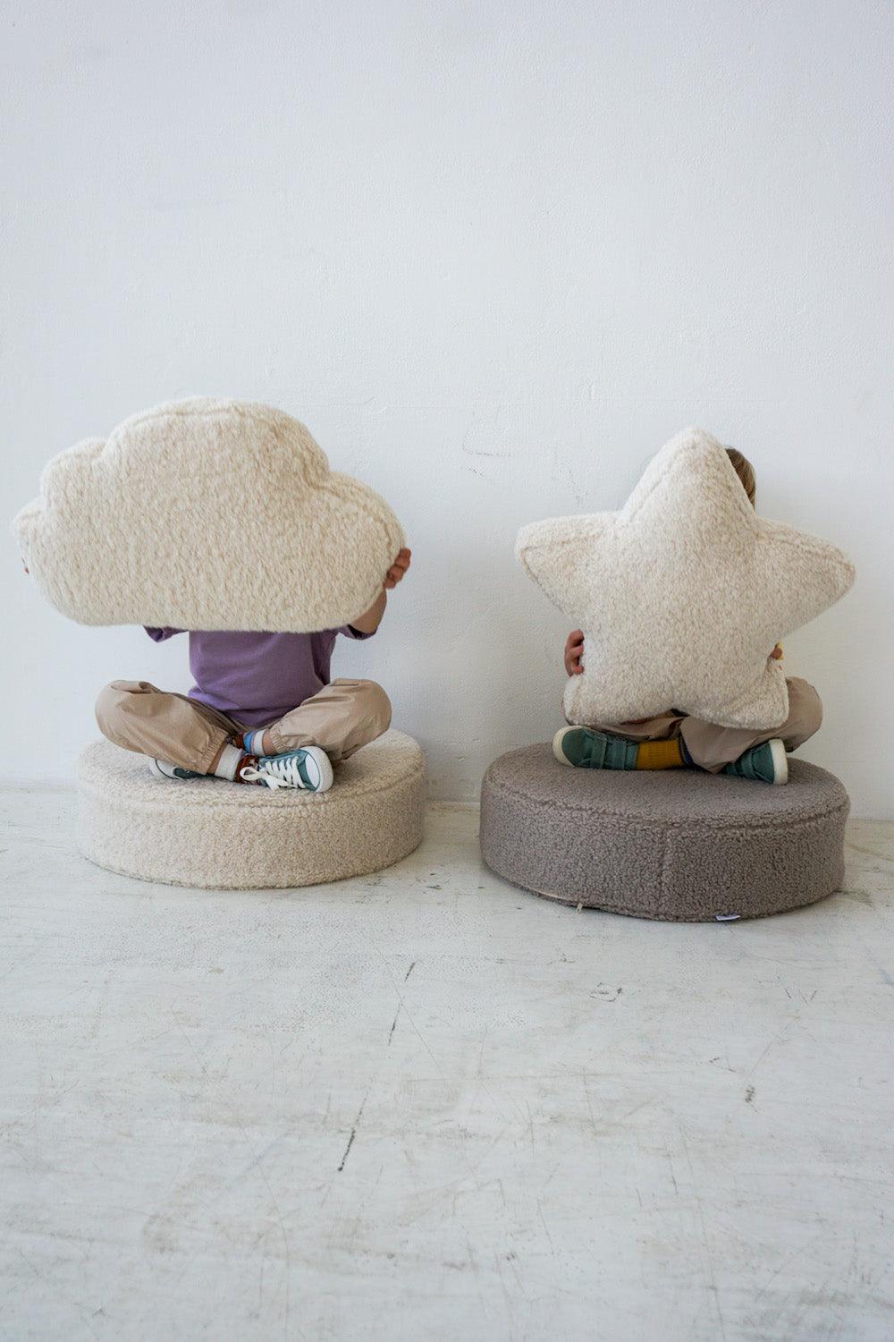 children sitting on large boucle poufs with boucle cloud cushion and boucle star cushion in hands  