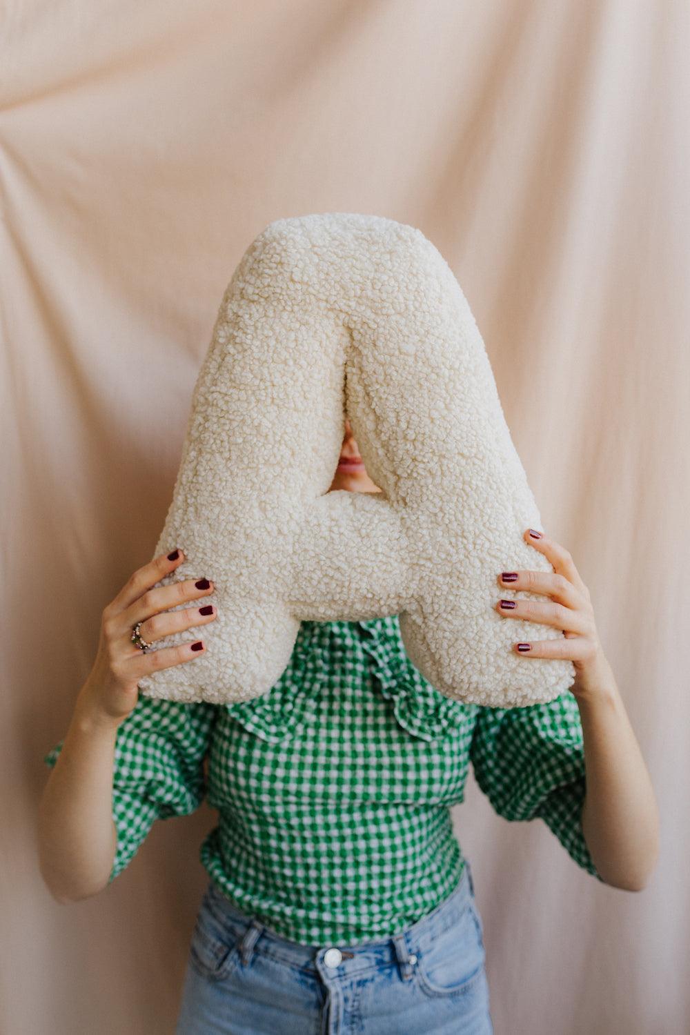 boucle letter cushion A teddy pillow by bettys home held by woman in green shirt in front of her 