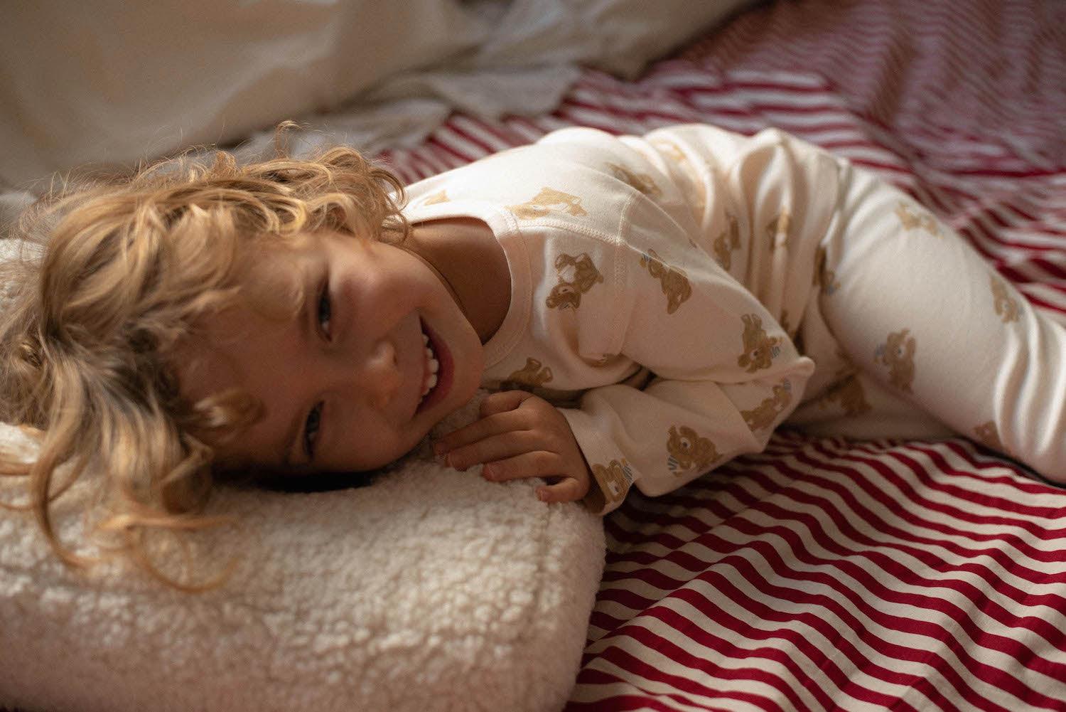 little boy lying on boucle letter cushion in his bed 