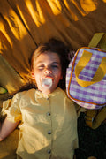 cute girl on yellow blanket with small checkered backpack. Gingham retro backpack